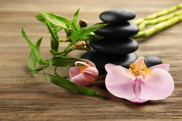 Spa stones, bamboo sticks and orchid flowers on wooden background