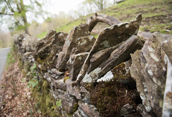 Old dry stone wall in the english countryside vanishing into the distance, with shallow depth of field