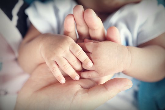 Photo of newborn baby feet and hand in soft focus