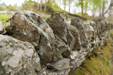 Old dry stone wall in the english countryside vanishing into the distance, with shallow depth of field