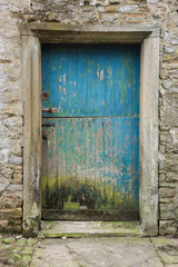 A blue weathered rustic, Old wooden farm stable door, set in a stone wall