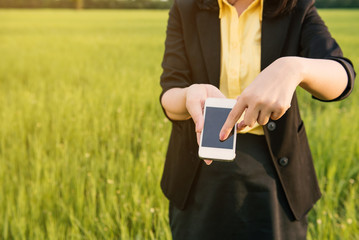 Close-up of a woman typing on mobile phone in green meadow