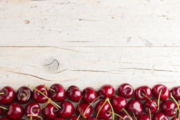 Border of fresh cherries on wooden background
