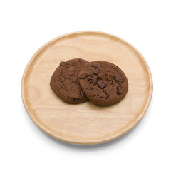 Chocolate cookies with chocolate chip on round wooden plate isolated on white background