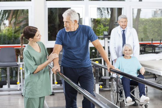 Man Looking At Physiotherapist While Doctor Pushing Woman In Whe