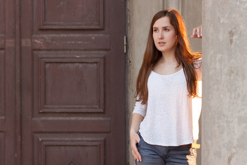 A young girl stands near an oldl door