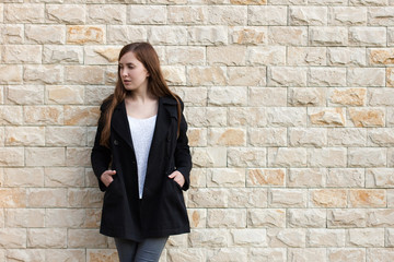 Girl in black coat near brick wall