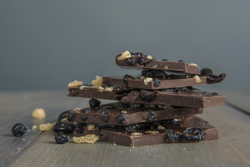 Stack of blueberry, cranberry, and ginger dark chocolate bark on gray wood table with blue background
