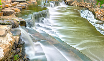 Fototapeta premium Close Rock waterfall with water flowing down smooth as silk sheet stone steps making natural scenery here beautiful and lyrical, idyllic countryside in Vietnam