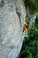 male rock climber. rock climber climbs on a rocky wall. a man hanging by one hand and resting