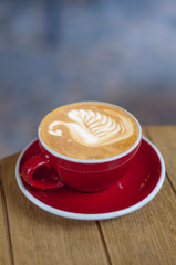 Red cup of fresh made espresso on wooden table