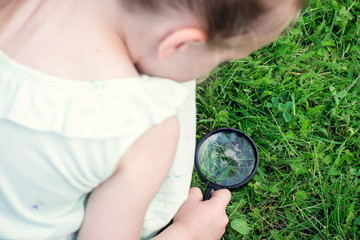 Girl looking at grass with a magnifying glass  