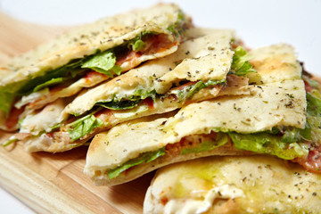 Pita bread with ham and fresh vegetables on the cutting board isolated on white