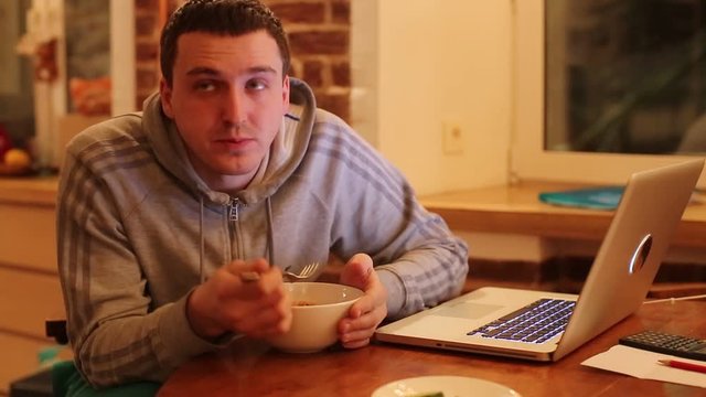A man reaps hot food evening in front of a laptop