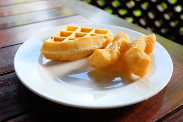 waffle and deep-fried doughstick on the plate in the table