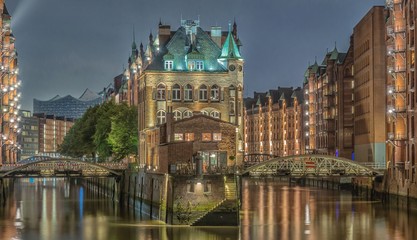 Fototapeta premium Speicherstadt in Hamburg bei Nacht mit Lichtern und Spiegelungen im Wasser