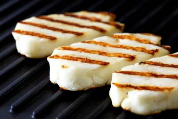 Gordijnen Three grilled slices of halloumi cheese on grill in perspective. With grill marks. © Moving Moment