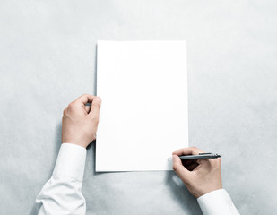 Hand holding blank agreement mockup and signing it. Arm in shirt hold clear document template mock...