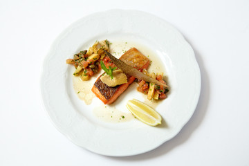 Grilled piece of salmon with vegetable and lemon isolated on white