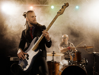 Rock band performs on stage. Bassist in the foreground.