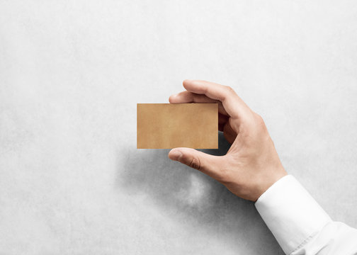Hand hold blank plain craft business card design mockup. Brown calling card mock up template holding arm. Visit pasteboard kraft paper display front. Small offset texture card print. Logo branding