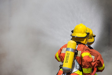 Fototapeta premium two firefighter in fire fighting suit spraying water to fire and