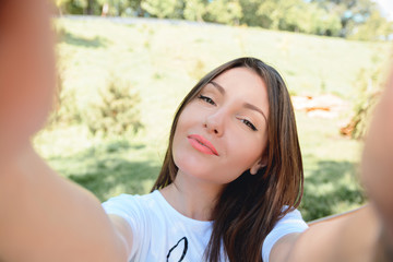 POrtrait of a smiling young girl making selfie photo in park