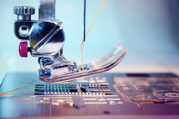 Needle and thread of an electric modern sewing machine. Very close up. Selective focus on thread.