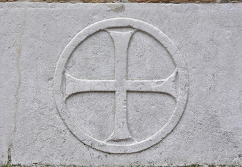 Old relief of a cross inside a circle on the wall of St Mary of Charity gothic church in Venice
