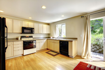 Brown wooden dining table in small kitchen room with black appliances.