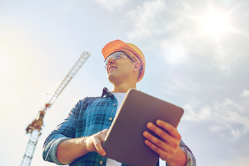 builder in hardhat with tablet pc at construction