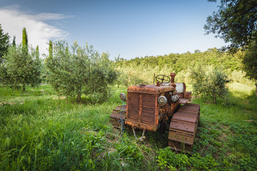 Old rusty tractor neglected under the tree