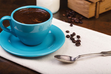 Cup of coffee and wooden containers filled with cofee beans