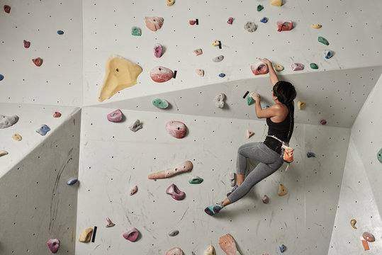 Girl climbing indoors, view from the back