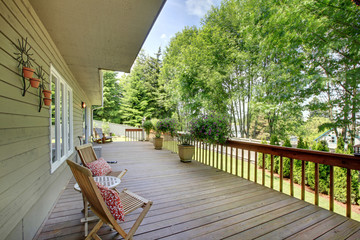 Wooden walkout deck with chairs and flower pots .