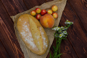 Свежий хлеб булка с цветами и фруктами на деревянном фоне