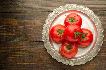 tomatoes on vintage plate top view, wooden background