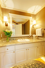 Luxurious bathroom interior with framed mirror and white cabinets.