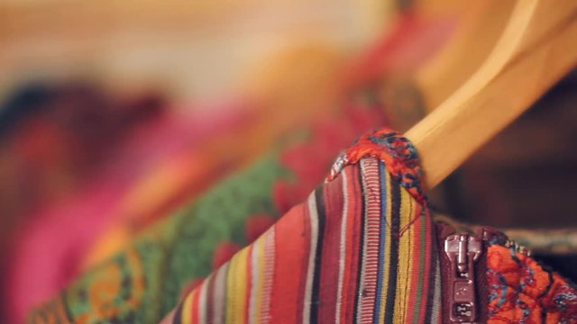 Close up shot of wide range of colorful traditional national uzbek  robes hanging in a store or souvenir shop on hangers in Uzbekistan. Rack focus.
