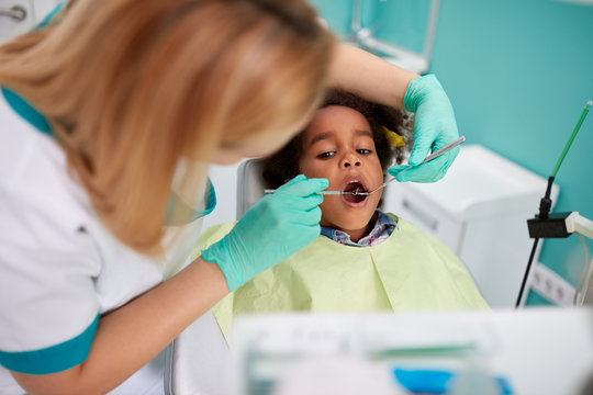 Dental assistant look with dental mirror girl’s teeth