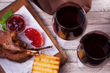 Red wine glasses. Rack of lamb with pomegranate sauce and greens. View from above, top studio shot