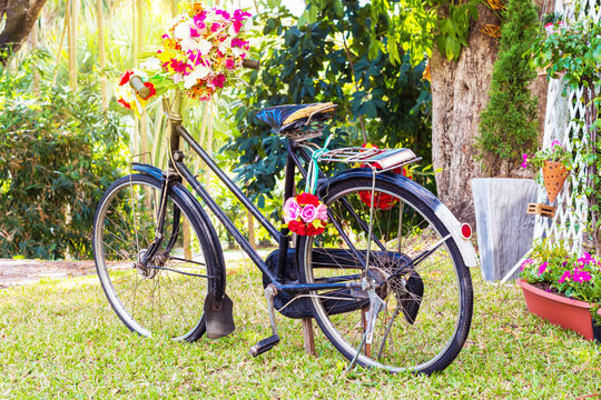 Vintage Bicycle with flowers on summer landscape background