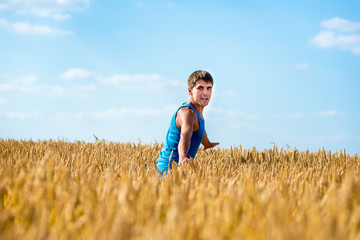 Naklejka na ściany i meble Young happy man in a wheat field.