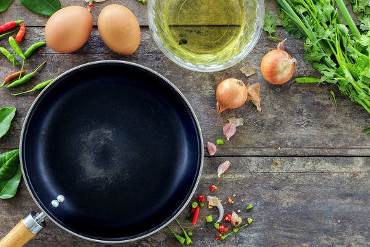cooking concept, frying pan and vegetables with eggs on wooden background, over light