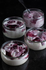 Yogurts with fruits assortment in glass bowls on dark marble background. Natural and fruit healthy, diet, gourmet dessert for granola breakfast. Sweet yoghurts closeup.