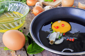 cooking concept, frying pan and vegetables with eggs on wooden background, over light