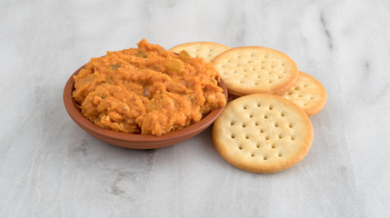 Spicy chicken salad in bowl with butter crackers on a gray marble cutting board.