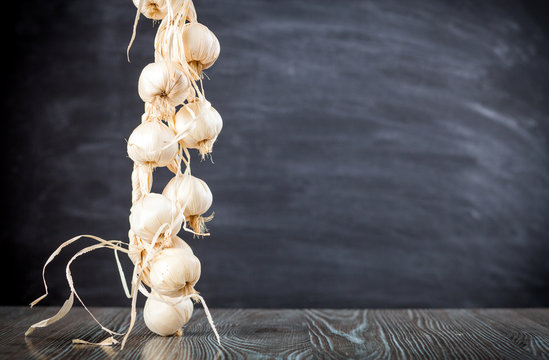 String of garlic on wooden table dark background copy space
