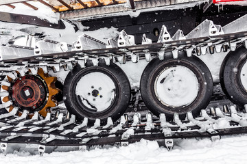 Fototapeta na wymiar snowcat detail at winter snow storm, caterpillar and wheel detail