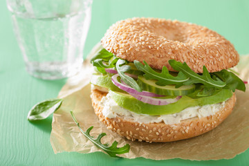 avocado sandwich on bagel with cream cheese onion cucumber arugu